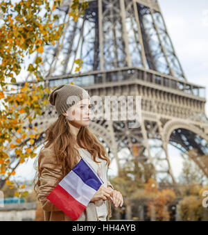 Autumn getaways in Paris. happy young elegant woman on embankment near Eiffel tower in Paris, France with flag Stock Photo