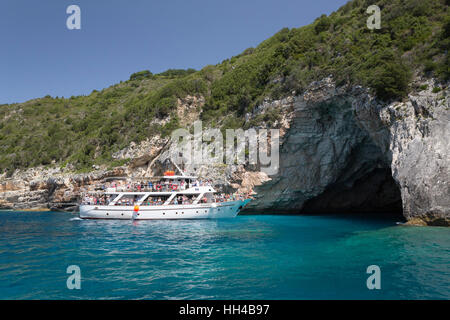 Tour boat entering into blue cave on west coast of island, Paxos, Ionian Islands, Greek Islands, Greece, Europe Stock Photo