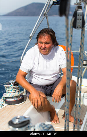 Young Man Sits On Yacht Board And Look To Left. He Talks On Phone. Guy 