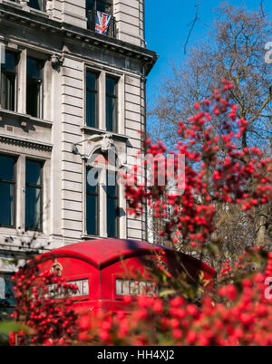 A British flag hangs in a window with a red telephone box in the foreground. Stock Photo