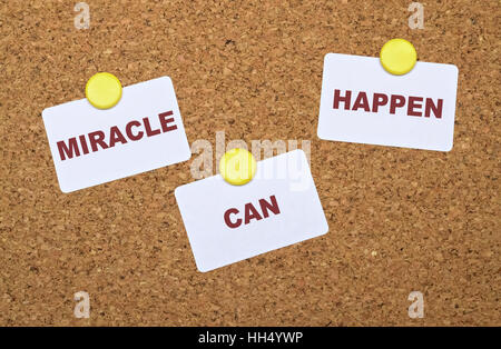 Text Miracle Can Happen on white stickers pinned on cork board Stock Photo