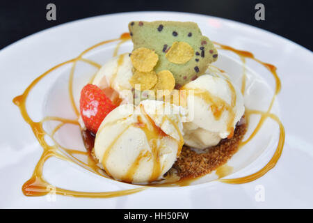 Ice-cream with syrup and strawberries on a white plateplate Stock Photo