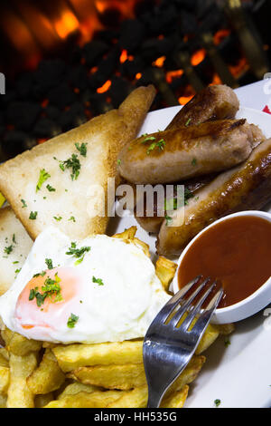 English pub dinner of Sausage, fried egg and chips/fries. Stock Photo