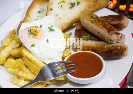 English pub dinner of Sausage, fried egg and chips/fries. Stock Photo