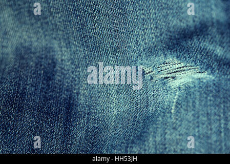 Word and faded denim jean material with a frayed hole in a horizontal composition in color. Stock Photo