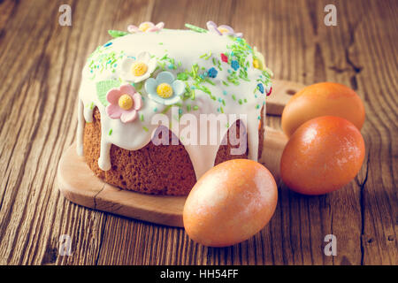Easter cake with glace icing decoration and colored easter eggs on a rustic wooden table Stock Photo