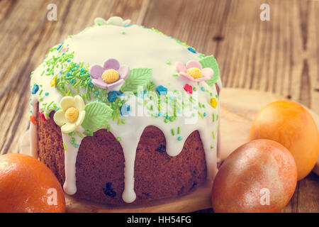 Easter cake with glace icing decoration and colored easter eggs on a rustic wooden table Stock Photo