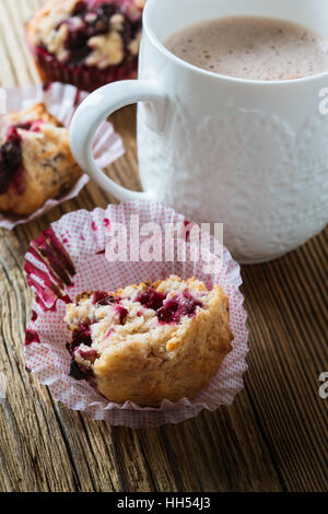 Cup cocoa with milk and homemade black berry muffins. Muffins with black currant for healthy breakfast on rustic wooden table Stock Photo