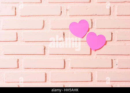 Pink sticky notes hearts shaped lined holes on the wall Stock Photo