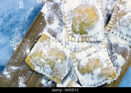 Floured italian ravioli with black pepper on a marble background Stock Photo