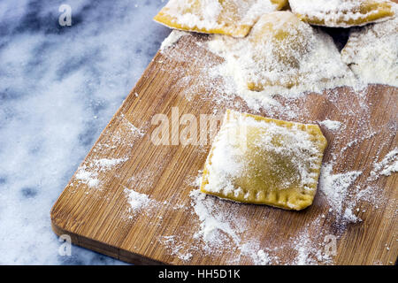 Floured Italian ravioli with black pepper on a marble background Stock Photo