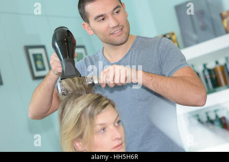 Male hairdresser drying woman's hair Stock Photo