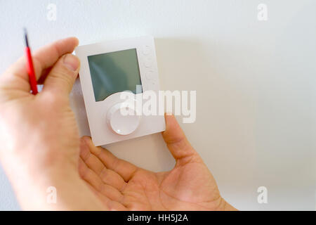 Electrician fitting a new thermostat Stock Photo