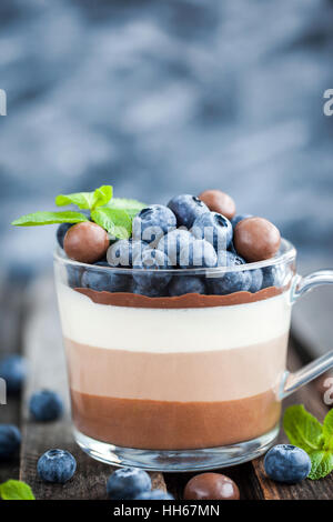 Delicious  three layered chocolate mousse dessert, devorated with fresh blueberry, mint and candies, served in glass cup Stock Photo