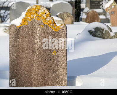 old tombstone with snow on and around it Stock Photo