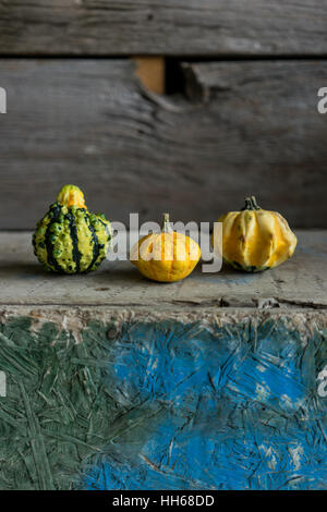 Still life with three gourds sitting on a vintage-looking wooden surface Stock Photo