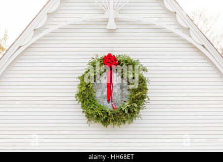Christmas wreath hanging on the outside of an old white building with interesting architectural details Stock Photo