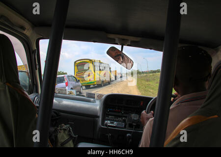 View from the backseat of a safari van while avoiding bad traffic in Nairobi (Kenya) with the driver's face seen in the rearview mirror Stock Photo