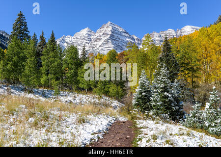 Autumn Snow at Maroon Bells - A hiking trail extending toward snow covered Maroon Bells. Aspen, Colorado, USA. Stock Photo