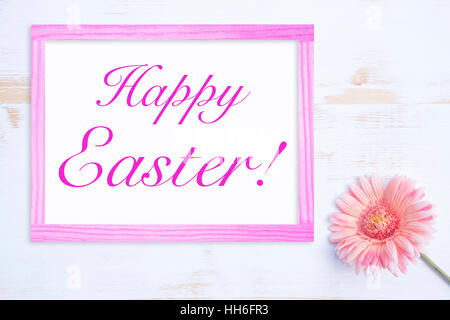 pink flower on white wooden table with frame and words Happy Easter Stock Photo