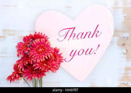 red flowers on wooden white table with heart and words Thank You Stock Photo