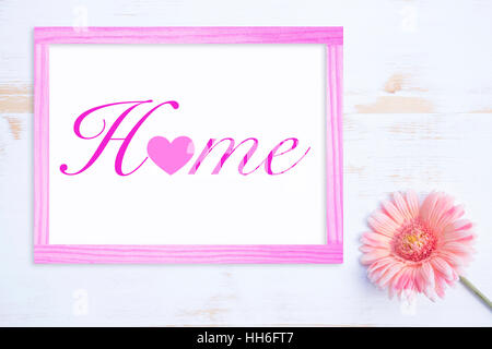 pink flower on white wooden table and frame with the word Home Stock Photo