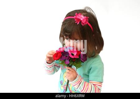 Little girl holding a bunch of flowers, child smelling flowers, spring concept, child, kid, sweet cute little girl, daydreaming Stock Photo
