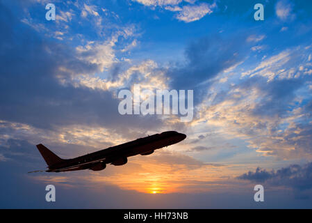 Silhouette of an airplane taking off, sunset background Stock Photo