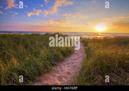 Path To A Sunset Beach. Winding trail through dune grass leads to a sunset beach on the coast of the inland sea of Lake Michigan Stock Photo