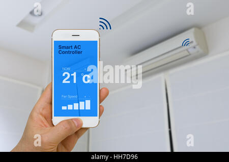 Concept of IOT, remotely controlling smart air conditioner with app on smartphone from distance. Stock Photo