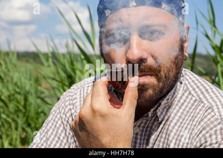 Bearded man smoking his pipe outside on a summer day Stock Photo