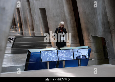 Jerusalem, Israel. 17th January, 2017. A woman touring the Yad Vashem Holocaust Museum stops by a video display. Adolf Eichmann is depicted in the screen on the right during his trial for war crimes in 1962. Credit: Nir Alon/Alamy Live News Stock Photo