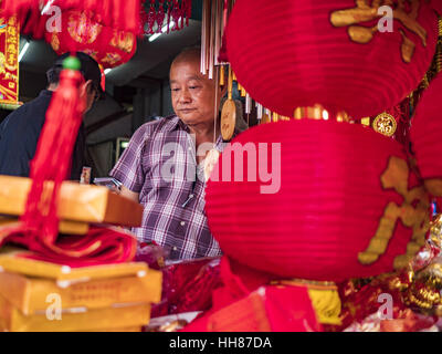 Bangkok, Thailand. 18th Jan, 2017. A man cuts red paper that a