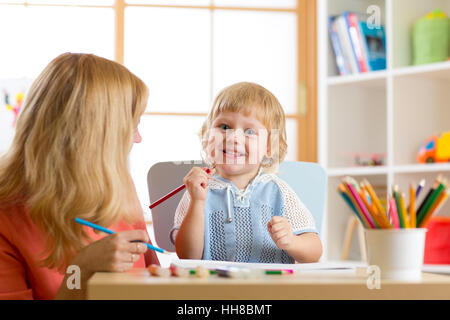 Happy family mother and kid together paint. Woman helps child boy. Stock Photo