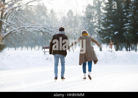 Senior couple in sunny winter nature ice skating, rear view. Stock Photo