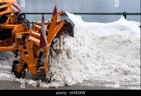 Truck With Snowplough Cleaning Road by Removing Snow from Road After Winter Blizzard Stock Photo