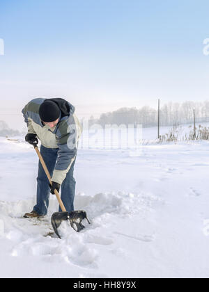 Man plowing his backyard with shovel after heavy snowing Stock Photo