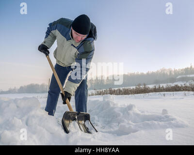 Man plowing his backyard with shovel after heavy snowing Stock Photo