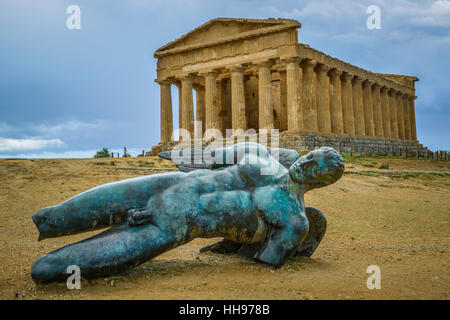 bronze statue of fallen ikaro on the background the concorde temple, Agrigento, Sicily, Italy Stock Photo