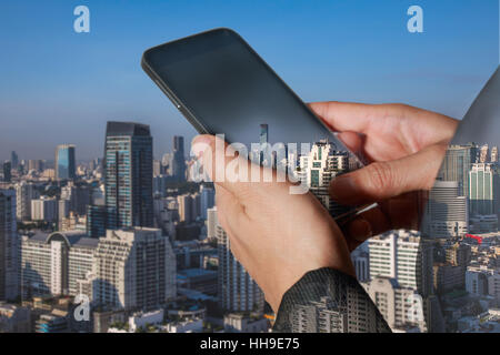 double exposure of woman hand hold and touch screen smart phone, tablet,cellphone and cityscape daytime Stock Photo