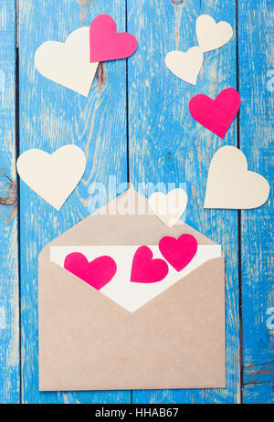 Envelope with handmade paper hearts and heart shape cookies on rustic wooden blue table. Valentines Day greeting card, top view Stock Photo