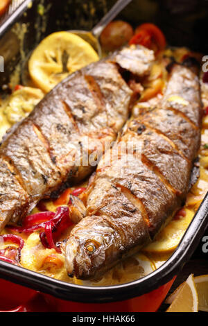Baked fish with lemon sauce and vegetables in a pan Stock Photo