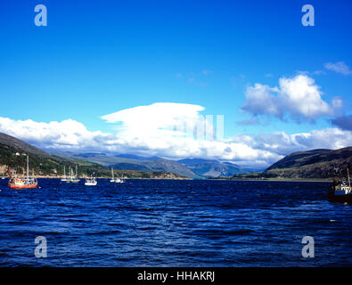 View of fishing boats moored in Loch Broom at Ullapool with Lenticular cloud passing across Beinn Dearg  Wester Ross Scotland Stock Photo