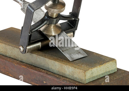 Close up Studio shot of chisel clamped in angle guide jig resting on grinding whetstones on white background Stock Photo