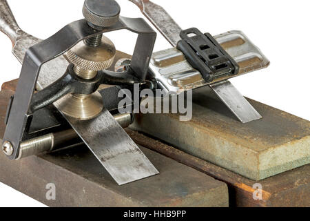 Studio shot of two chisels clamped in angle guide jigs resting on grinding whetstones on white background Stock Photo