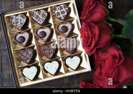 Box of romantic heart shaped chocolates and red roses. Stock Photo