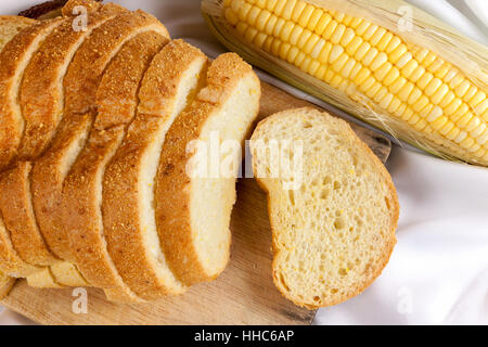 bread made from corn on the white fabric. Slices of corn bread laying on a chopping Board and Sweet corn cobs Stock Photo