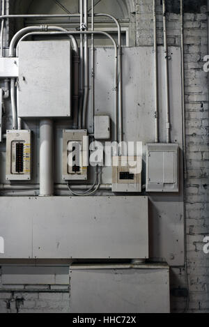Electrical wiring, switches and boxes and panels on a painted brick wall Stock Photo