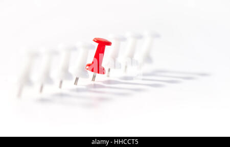 Red push pin in the middle of white push pins against a white background Stock Photo