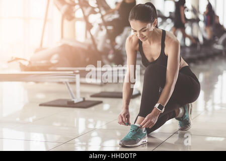 Pretty woman tying shoelaces in a gym Stock Photo